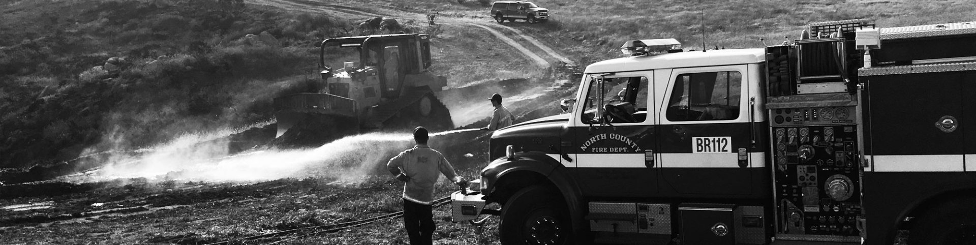 North Country fire trucks hose down dirt roads with the help of tractor