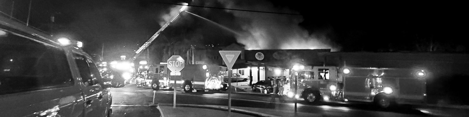 firetrucks pull in front of burning building at night